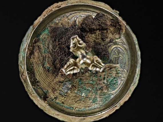 Top view of a silver round vessel with a gilded lid engraved with various round and organic shapes