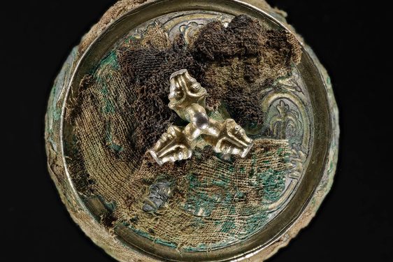 Top view of a silver round vessel with a gilded lid engraved with various round and organic shapes