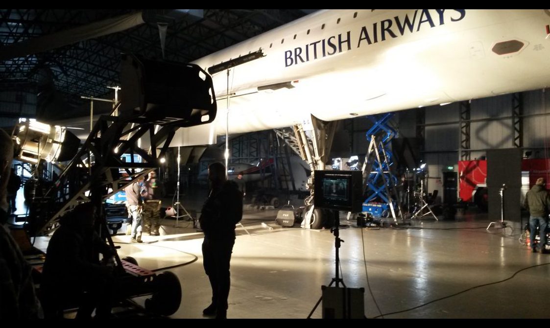 The silhouette of a film crew and equipment back lit under the Concorde jet.