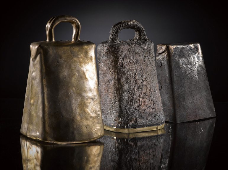 Three hand bells, two of which have handles on the top. One bell is covered in worn fabric.