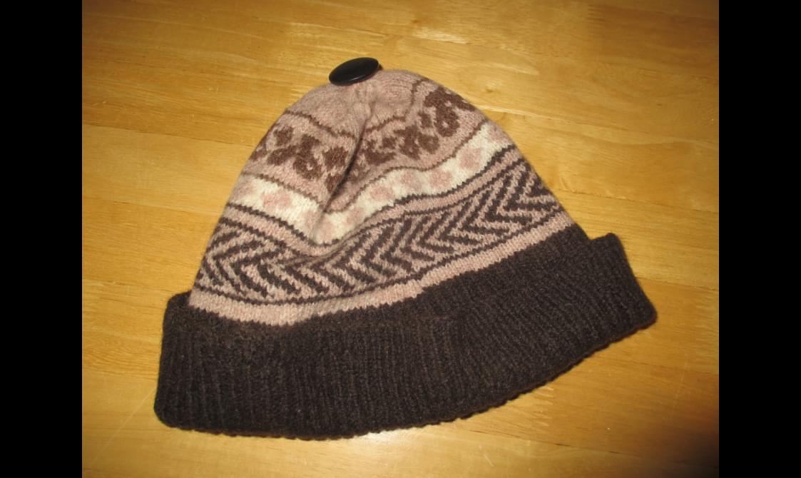 A fair isle patterned knitted hat knitted in brown and white wool.