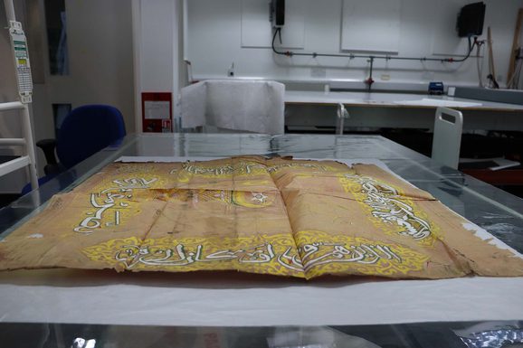 A piece of yellow-toned paper is placed within a chamber on a steel-grey table