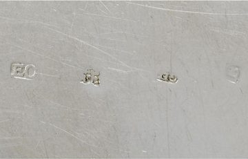 A silver surface with the initials EO as well as other embossed markings.