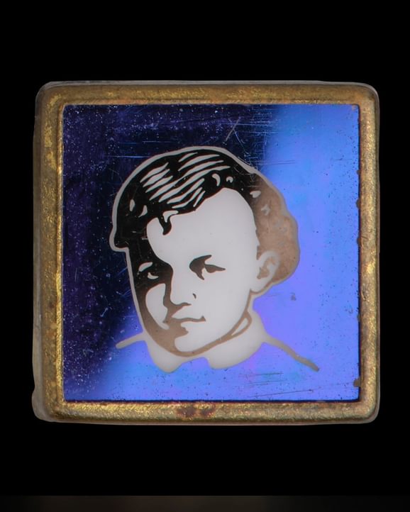 An image of Lenin as a young boy, set against a blue background with a gold coloured frame.