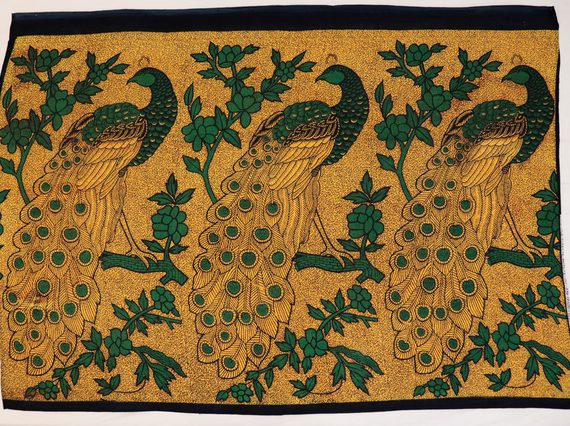 Gold textile with pattern of large black and green peacocks perched on branches.