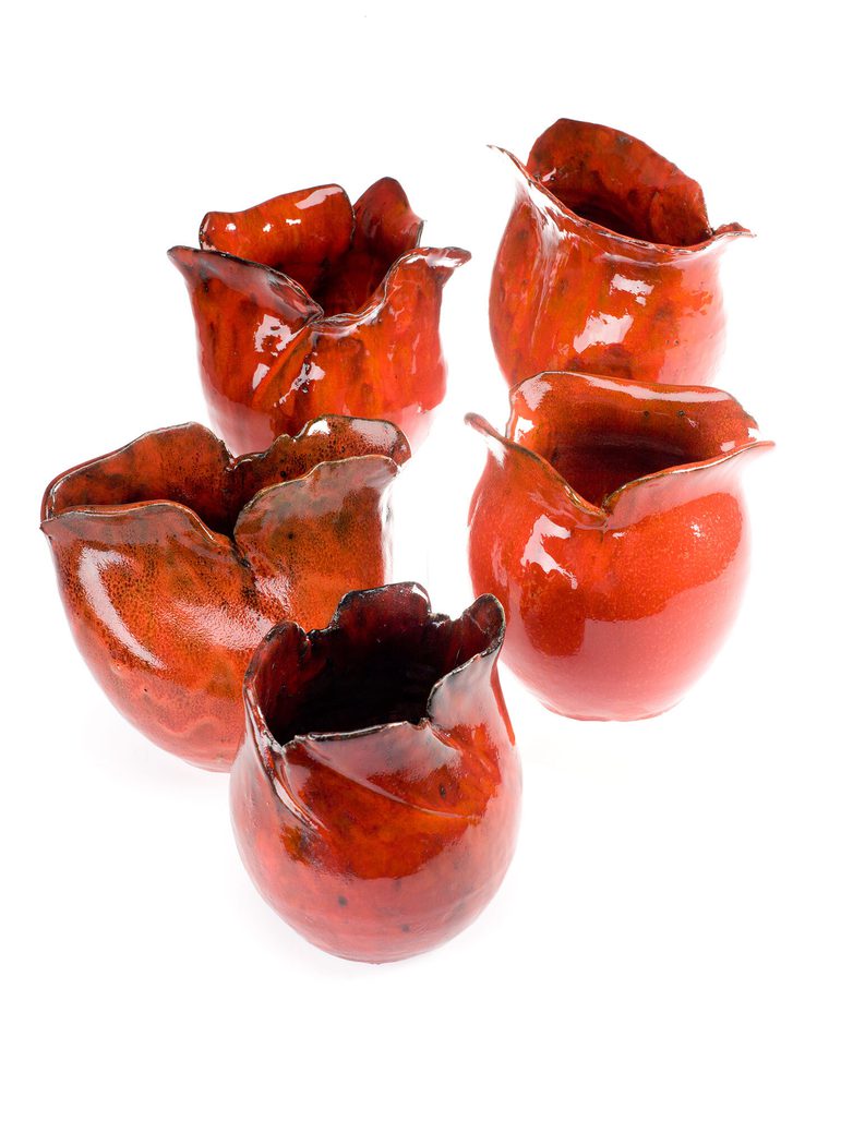 Five ceramic sculptures of red slightly closed poppy heads with black detailing.