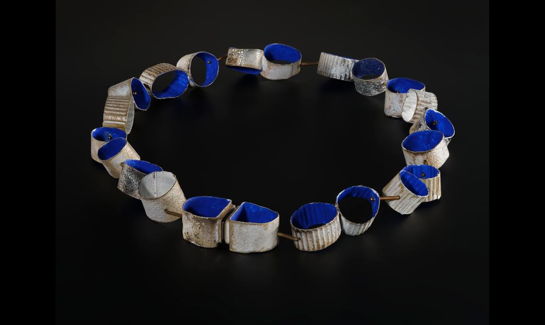 A necklace of multi-coloured laminated, carved acrylic segments, with striped and polka dot decoration and five abstract fruit and foliage forms at equal intervals around the collar.