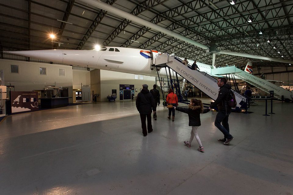 People walking around the Concorde in a large aircraft hangar.
