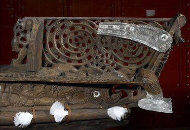 The stern of an intricately carved wooden canoe with details made of see-through perspex added.