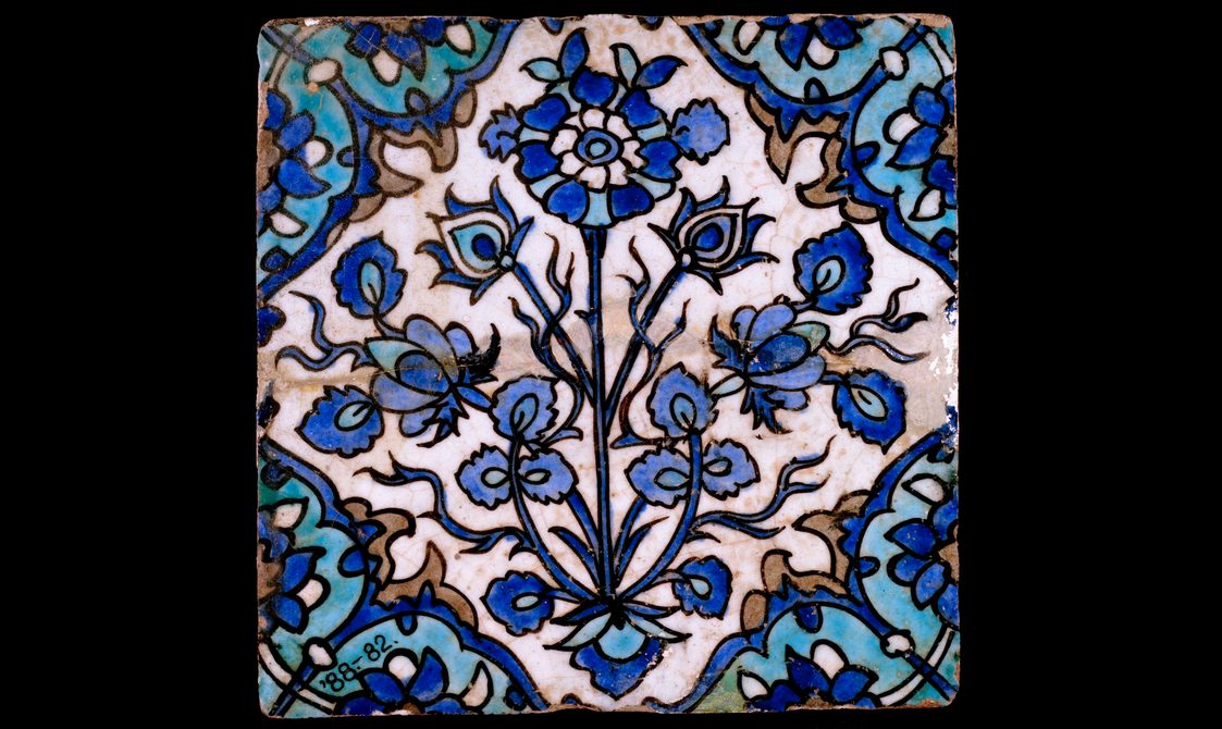 A blue and white square tile with an intricate floral pattern