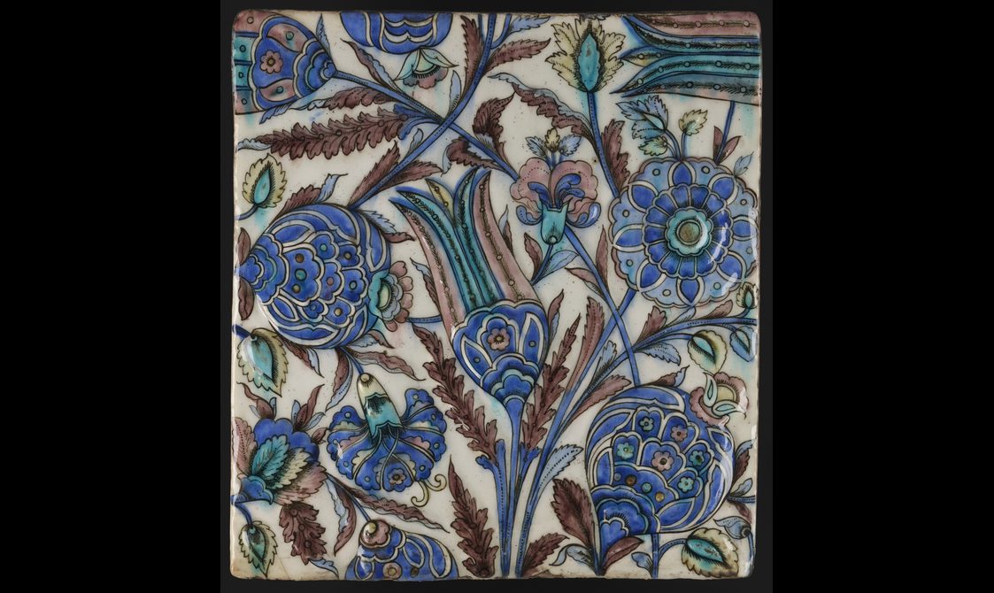 A white square tile decorated with blue flowers