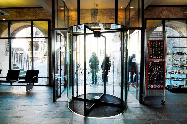 Two people entering a set of revolving doors into a museum.