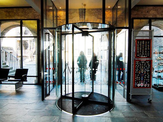 Two people entering a set of revolving doors into a museum.