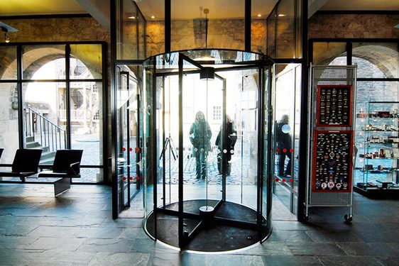 Two people entering a set of revolving doors into a museum.