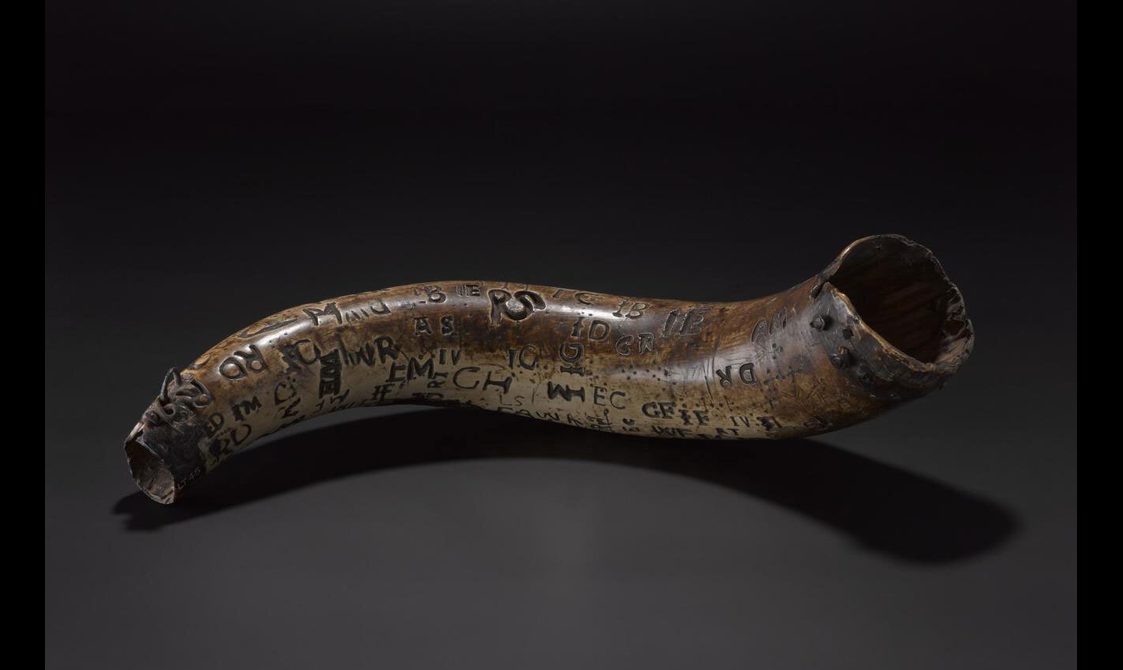 A curved horn with text and symbols covering the surface