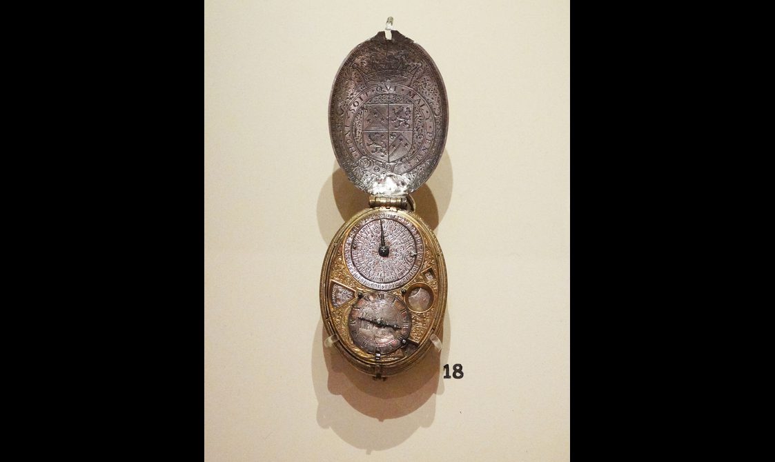 An elaborate silver and gold pocket watch with a royal crest and two dials.