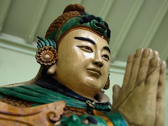 Close up of the head and praying hands of a Buddhist Weituo sculpture.