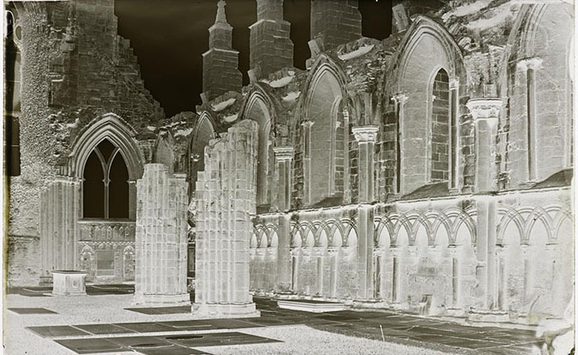 A black and white photographic negative of a partially ruined abbey.