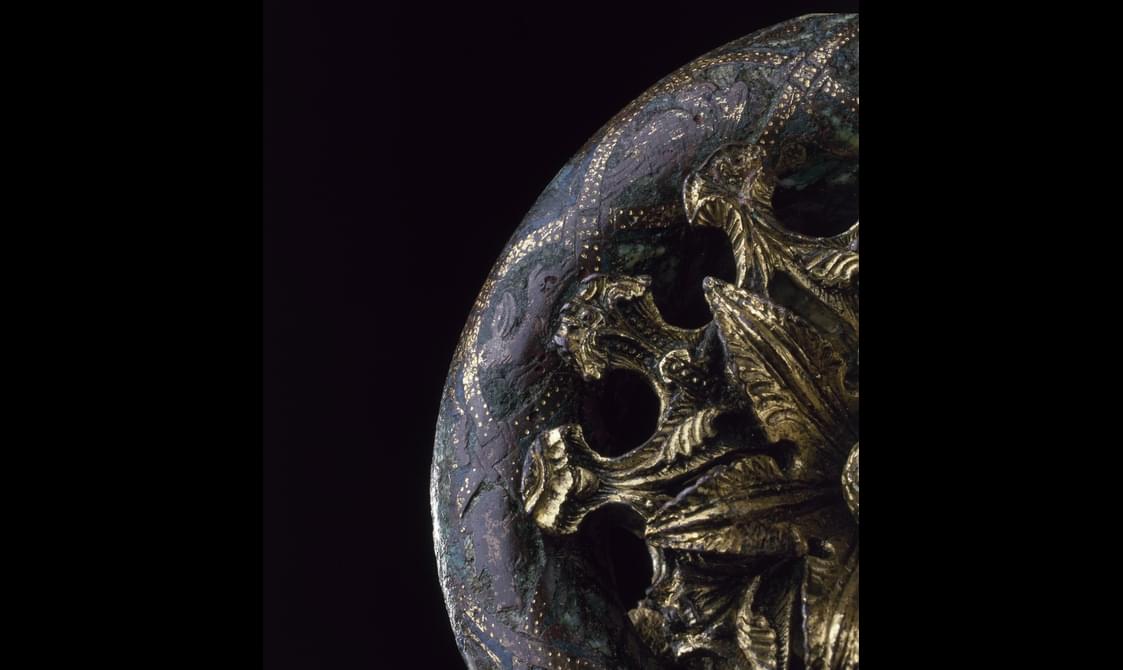 Closeup of the coiled top section of the crozier, revealing leaf details in the golden burst and fine golden criss-cross pattern on the metal staff.