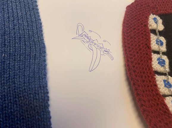 A piece of paper with a sketch with knitting samples in blue and red on top.