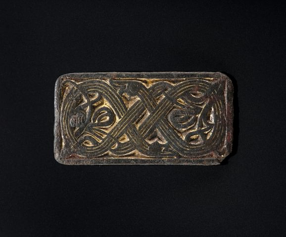 A bronze rectangular mount with a Celtic design inscribed on it
