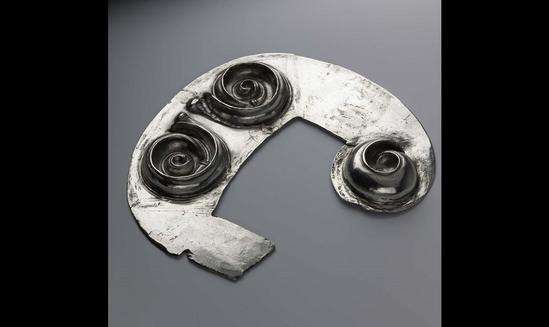 Silver sheet in a shape of a crescent with three sticking out spirals.