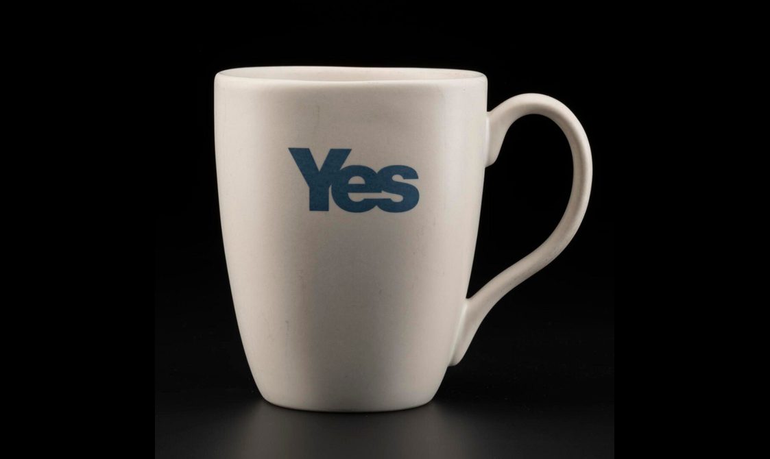 Simple white mug, tall but not overly so, with an earlobe-shaped handle and the word 'YES' written in indigo blue sans-serif font.