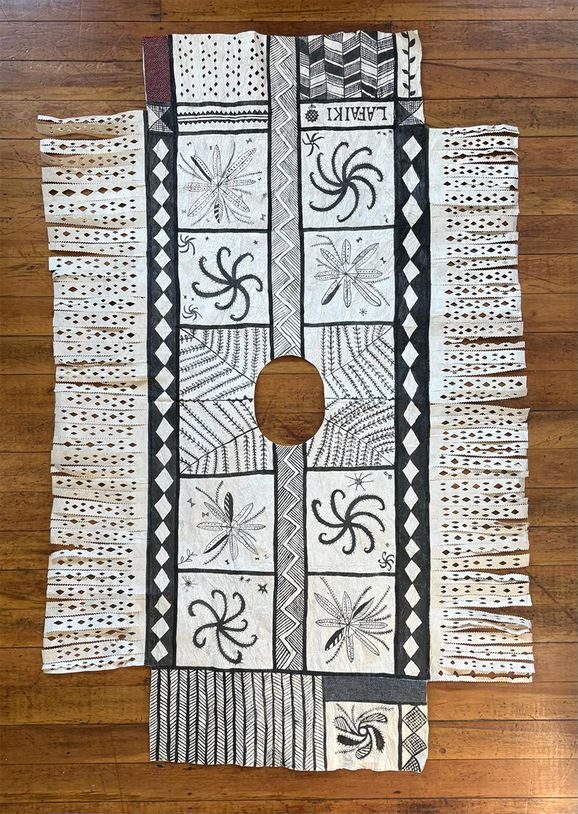 A black and white barkcloth poncho with nature illustrations and woollen textile offcuts