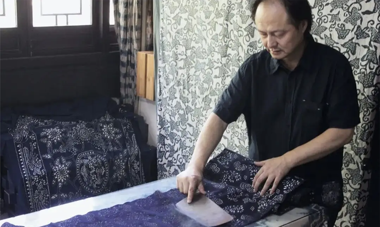 A man in a studio space with woodblock printed cloth