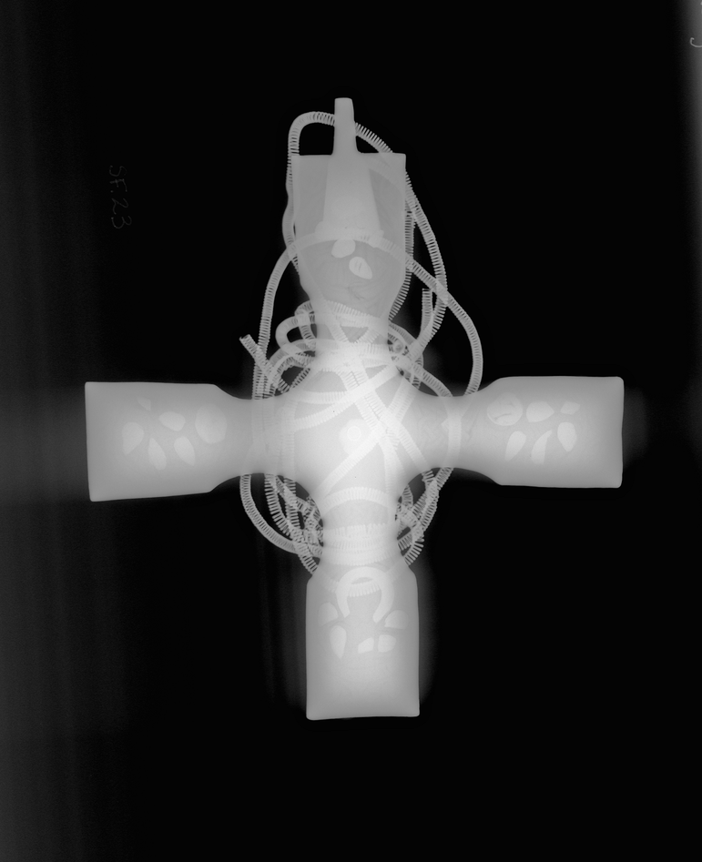 A black and white x-ray of a celtic cross with a chain wrapped around it