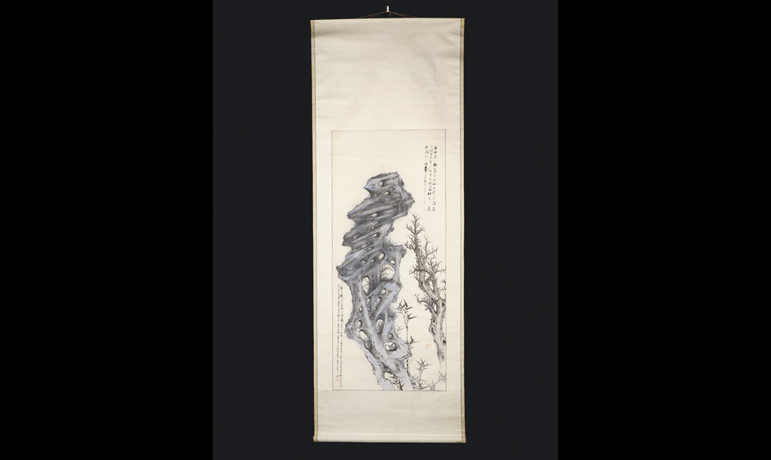A long rectangular hanging scroll painting depicting a stylised rock with grass or orchids, plum blossom and bamboo.